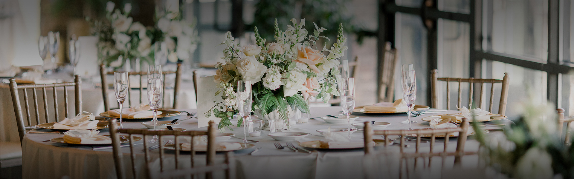 close up of a linen covered table with bamboo chairs and a large floral centerpiece