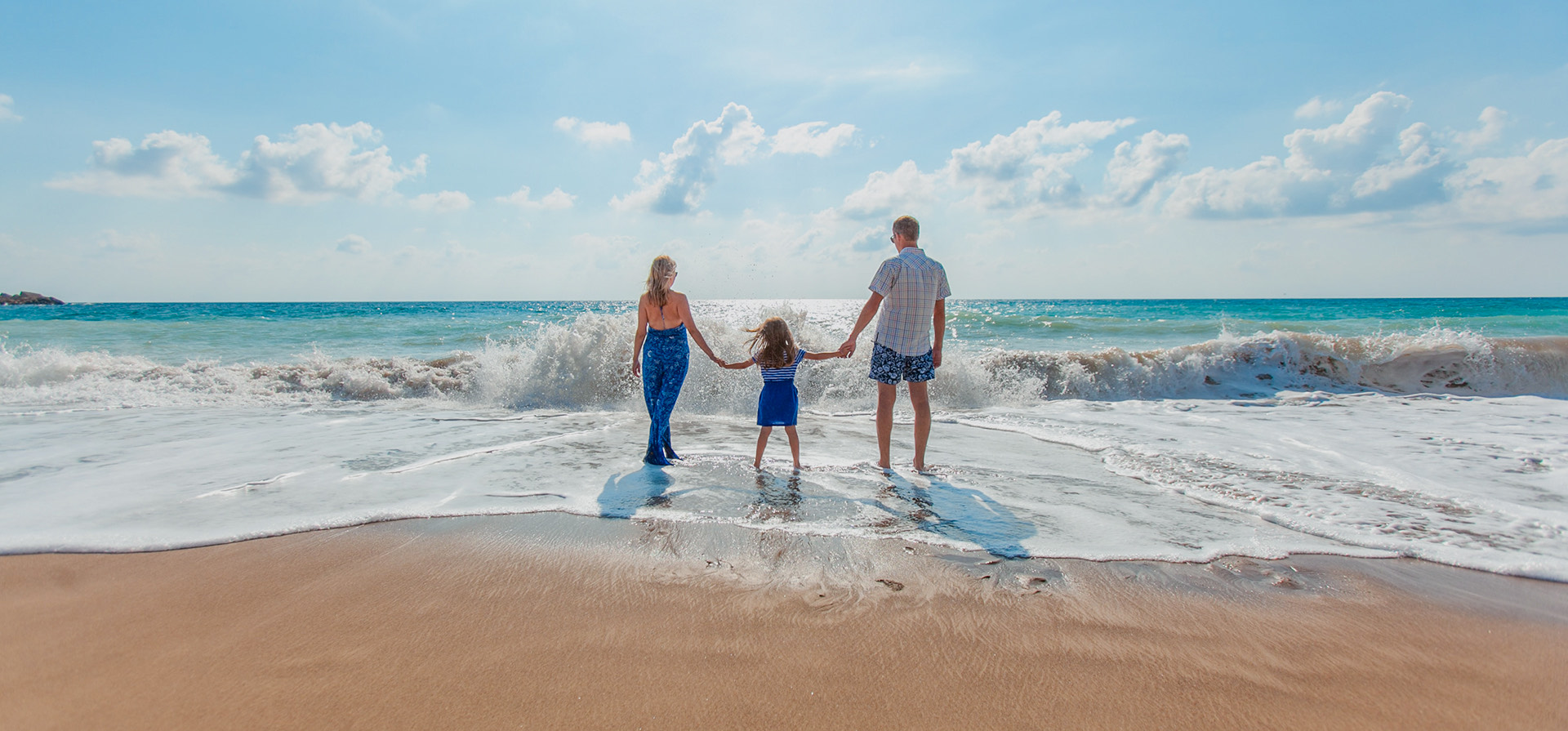 Mother and father with their child walking along the beach 