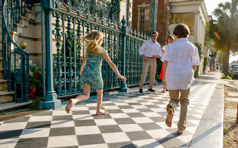 Two young kids running toward adults in front of hotel