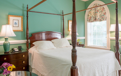 Room with king bed, wooden bed frame, nightstands & mint green wall