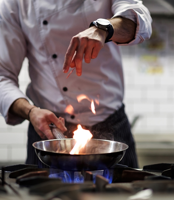 chef pan sautéing with a flame