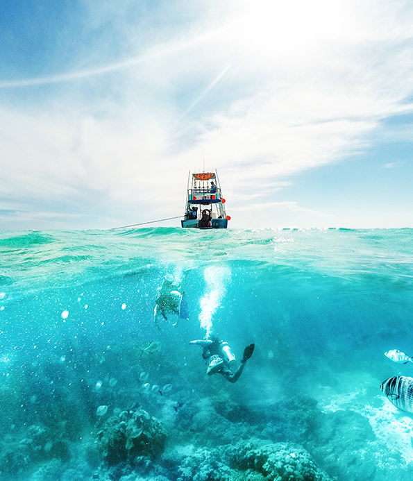 two divers underneath a dive boat