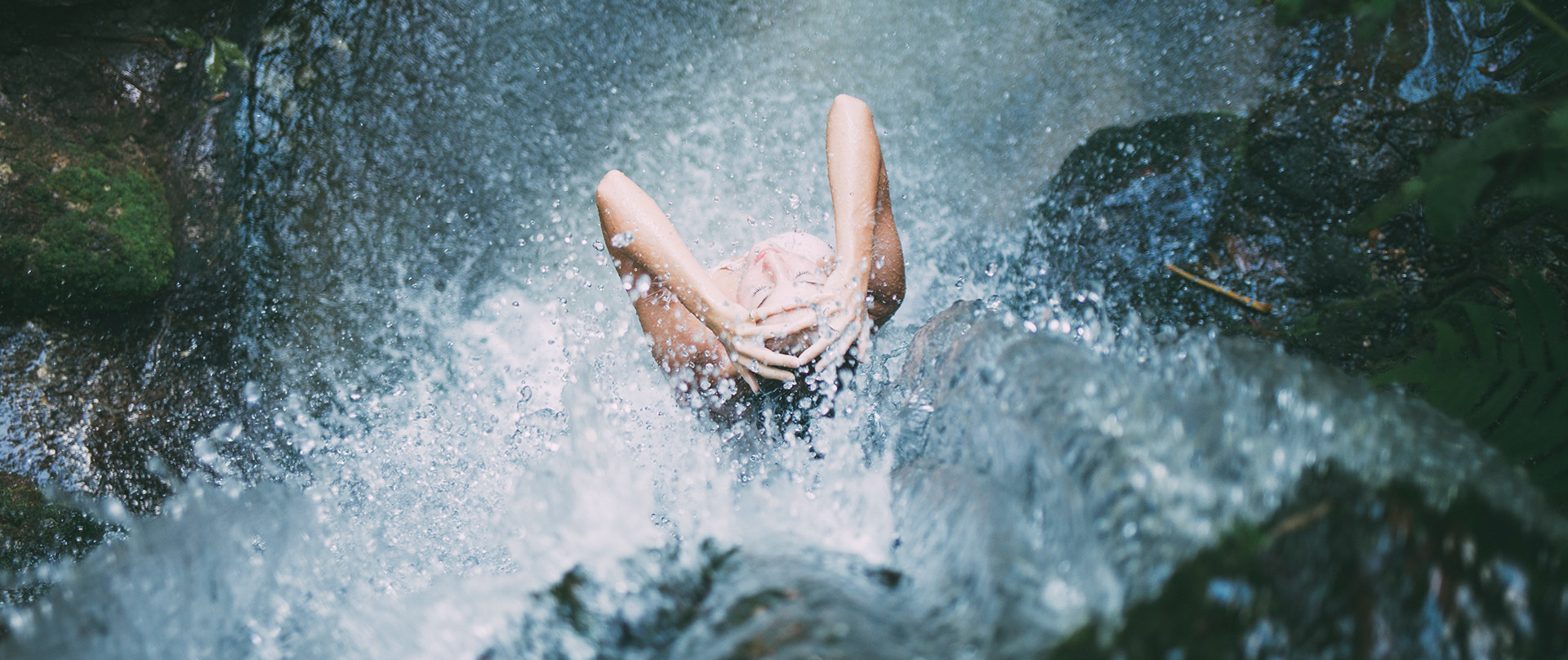 woman standing underneath a waterfall