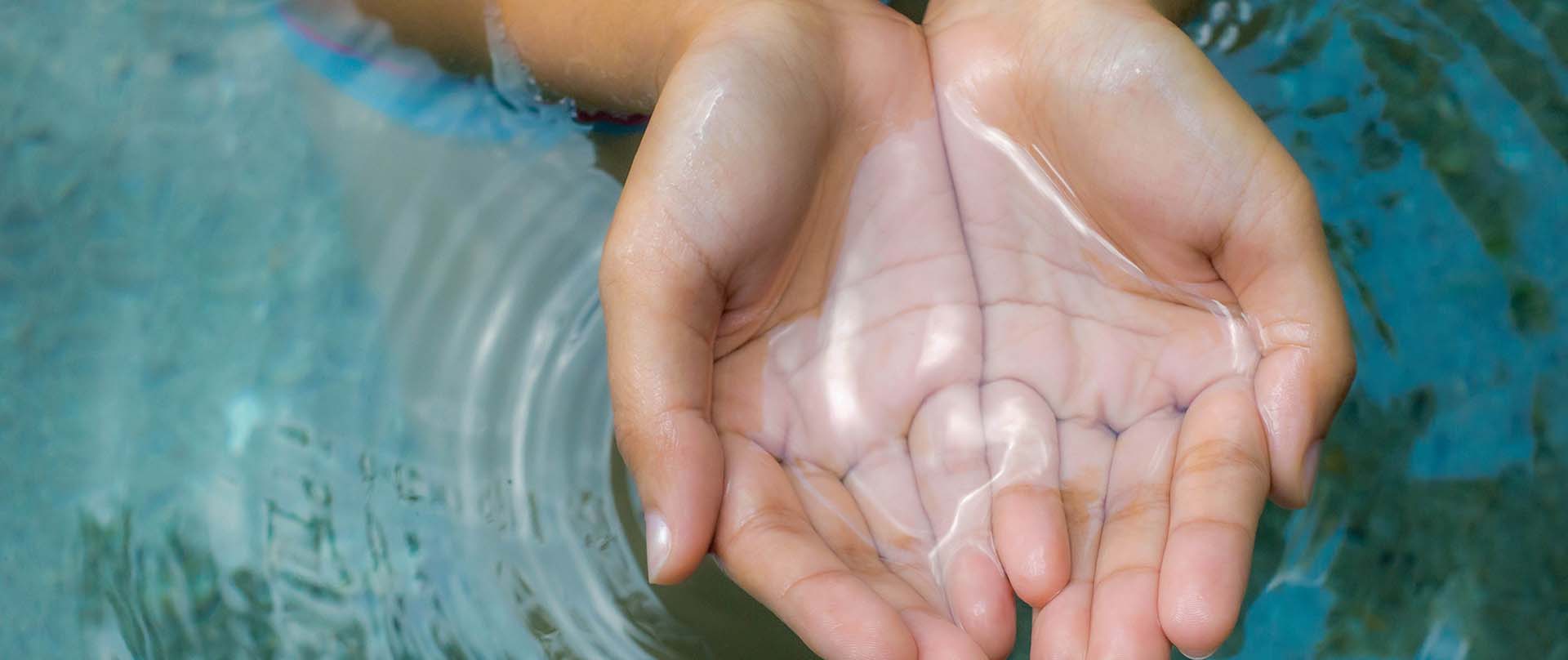 hands cupping water from a stream