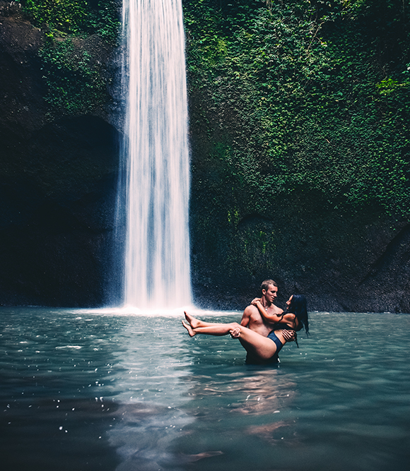 man carrying woman by a waterfall