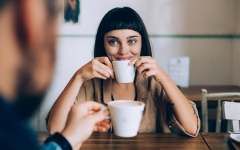 a woman golding a cup of coffee smiling 
