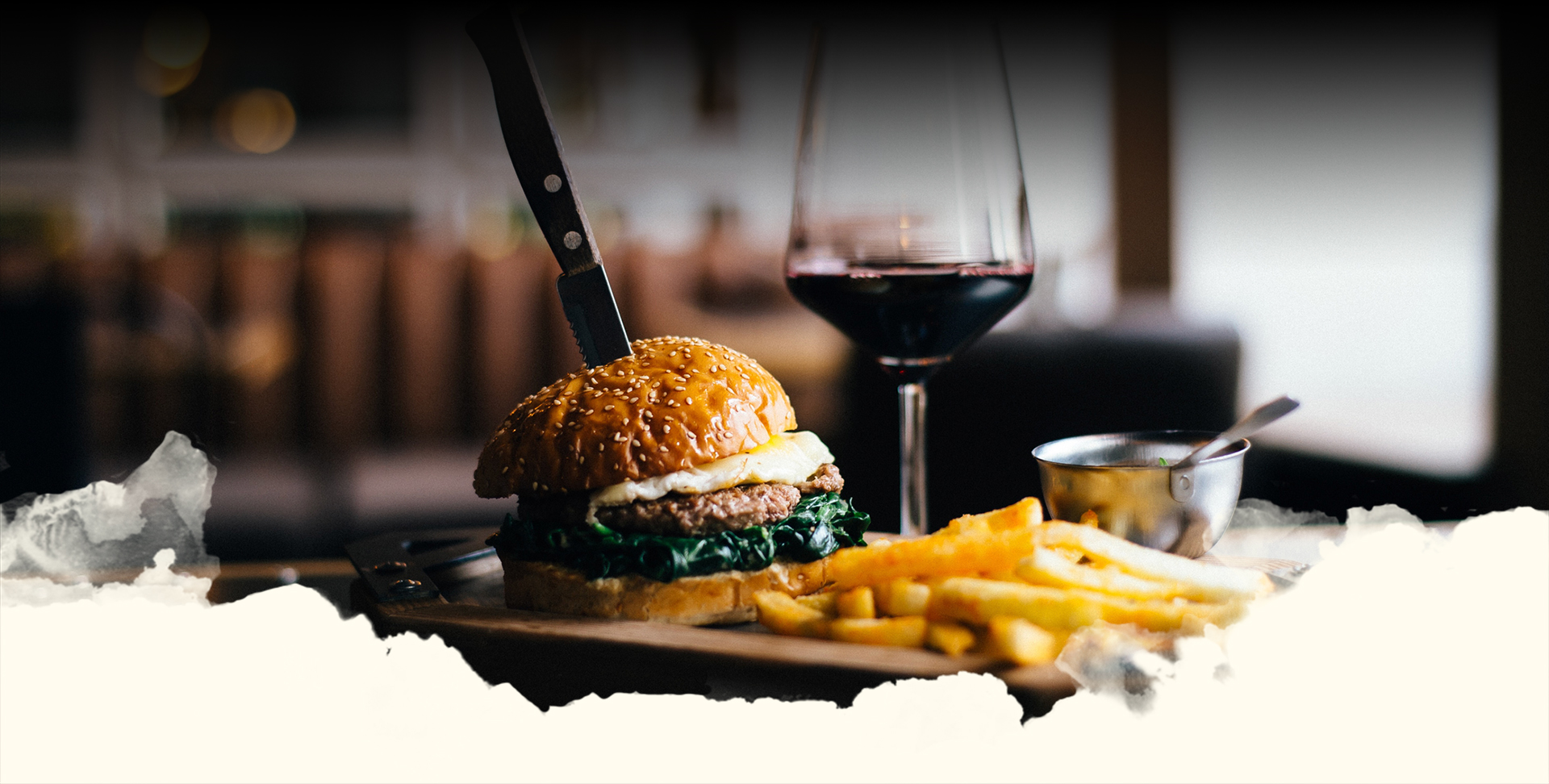 a burger with fries in a plate with a glass of wine