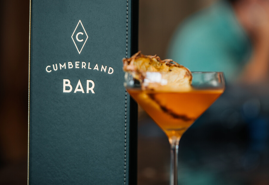 cocktail with garnish next to standing drink menu