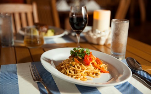 view of an elegant setup table with a glass of wine and a fettuccine dish
