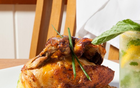 close up view roasted chicken served with potatoes and herbs