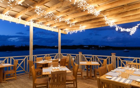 View of a dining area with wooden tables and romantic lightning at night 