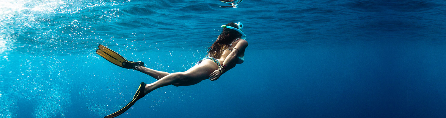 Woman swimming toward surface wearing scuba gear