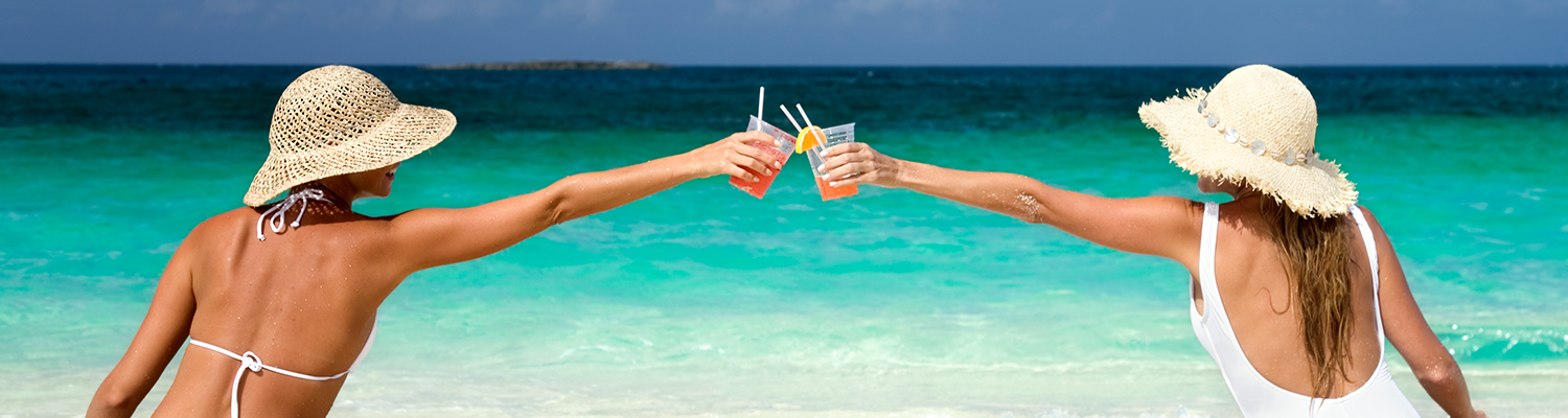 two women having a toast with cocktails on the shoreline