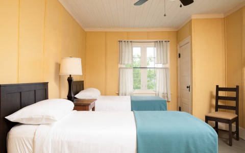 double twin beds with yellow walls and blue blankets 