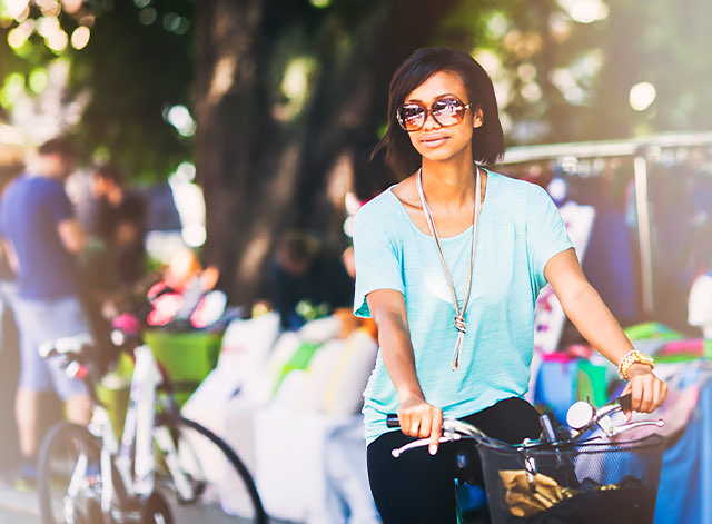woman riding a bike with sunglasses and a blue shirt on