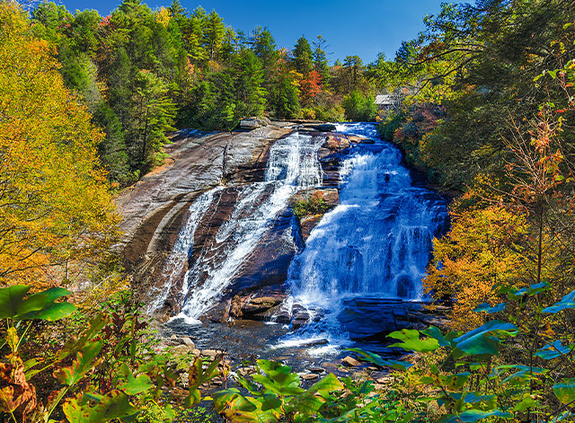 View of a big and wonderful waterfall surrounded by colored trees on a sunny day