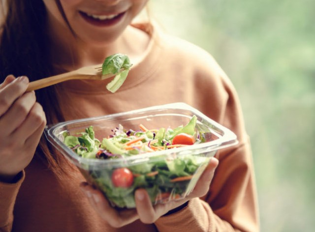 A young woman eating a big salad