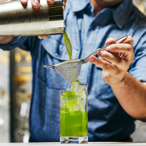bartender making a lime green cocktail
