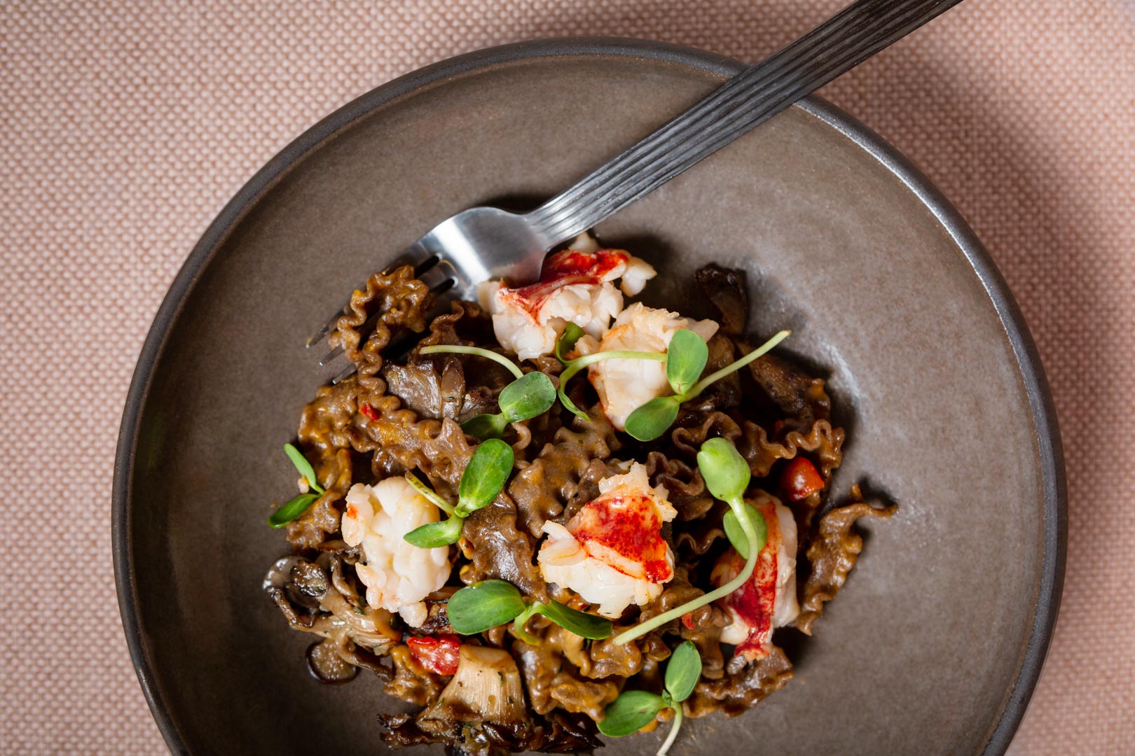 aerial view of plate of pasta with greens and lobster
