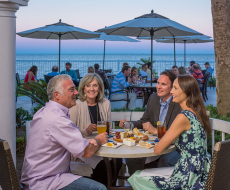 two couples engaging in dinner conversation at oceanside restaurant
