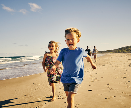 two kids running happily on the beach