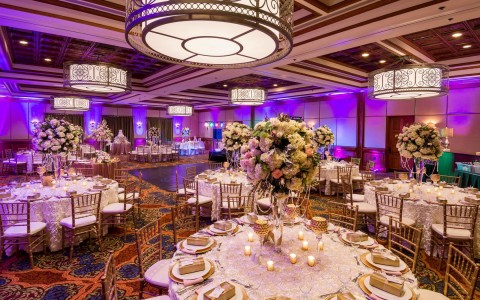 wedding event space room with purple lights and white flower centerpieces