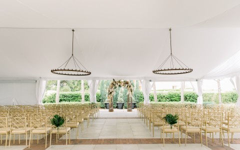 farmhouse wedding venue with natural wood chairs and round chandeliers 