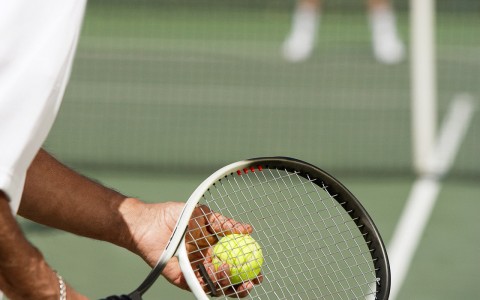 older man lining up a tennis serve on a grass court