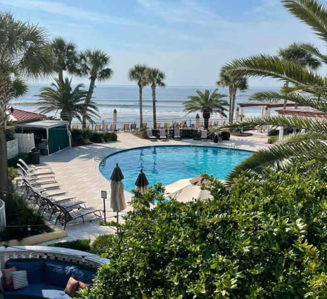view of resort patio circled by sun lounge chairs with view of ocean