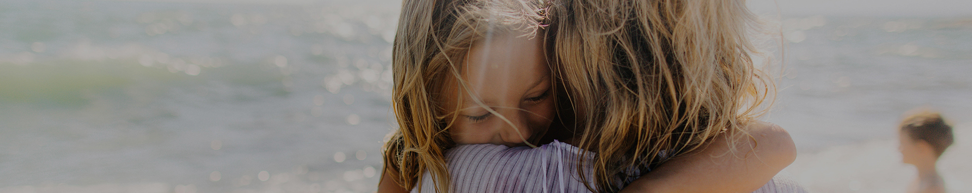 little girl hugging her mom on the beach