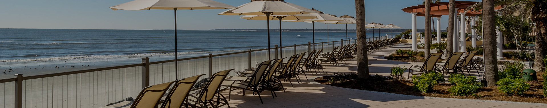 view of resort boardwalk lined with sun lounge chairs and umbrellas