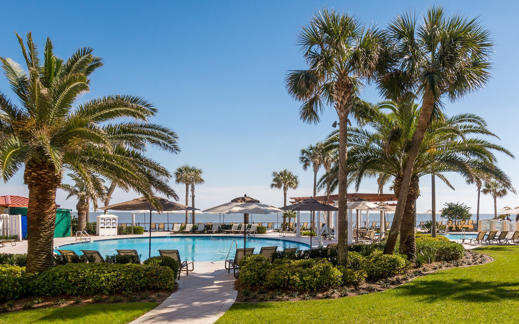view of resort pool with sun lounge chairs along ocean coast line