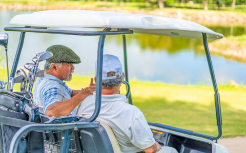 Side view of two mature men on a golf car