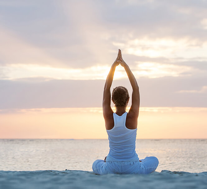 A woman practicing yoga next to the beach