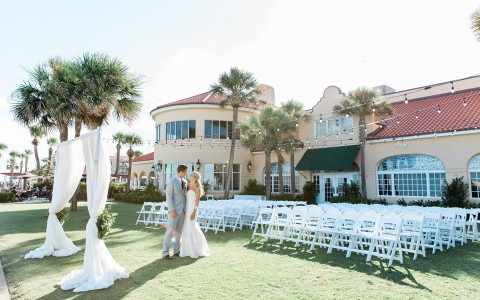 bride and groom with their arms around each other standing in the oceanfront lawn
