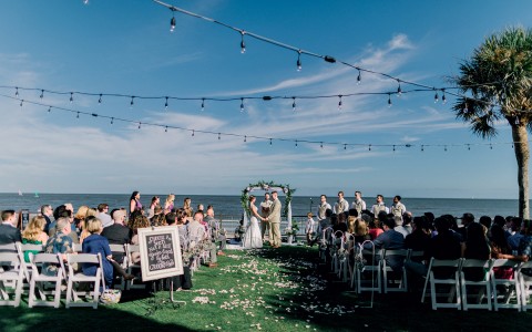 view of guests attending a wedding at the oceanfront lawn