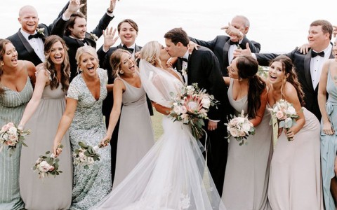 bride and groom kissing while the bridesmaids and groomsmen react