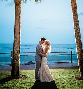 bride and groom hugging with the ocean in the background