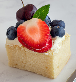 close up view of a slice of vanilla cake topped with fruit
