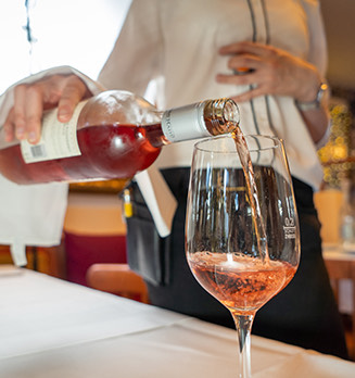 view of a waiter pouring wine into a glass