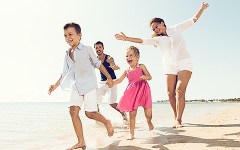 kids playing on a white sandy beach in color clothing with mom