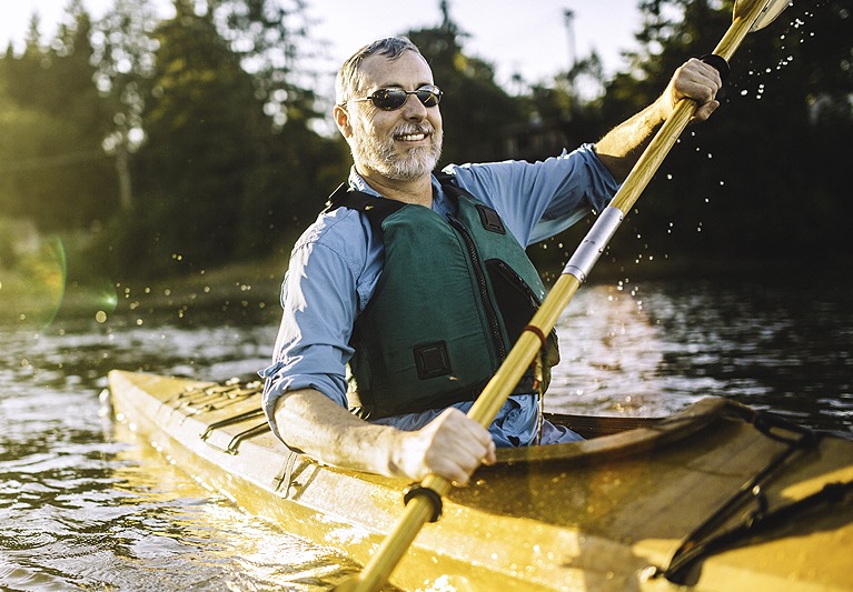 Man in green life vest rowing kayak