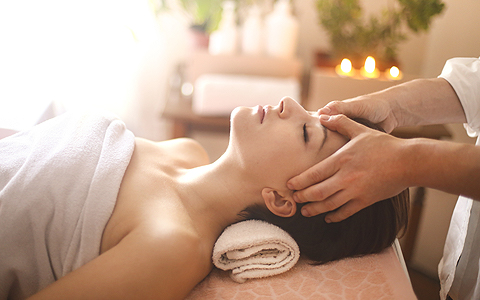 Woman laying on bed at spa as she gets a temple massage