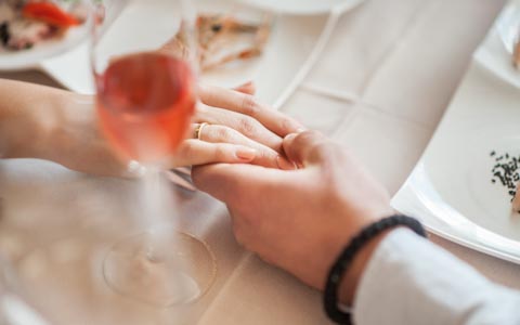 man holding a womans hand with a glass of rose