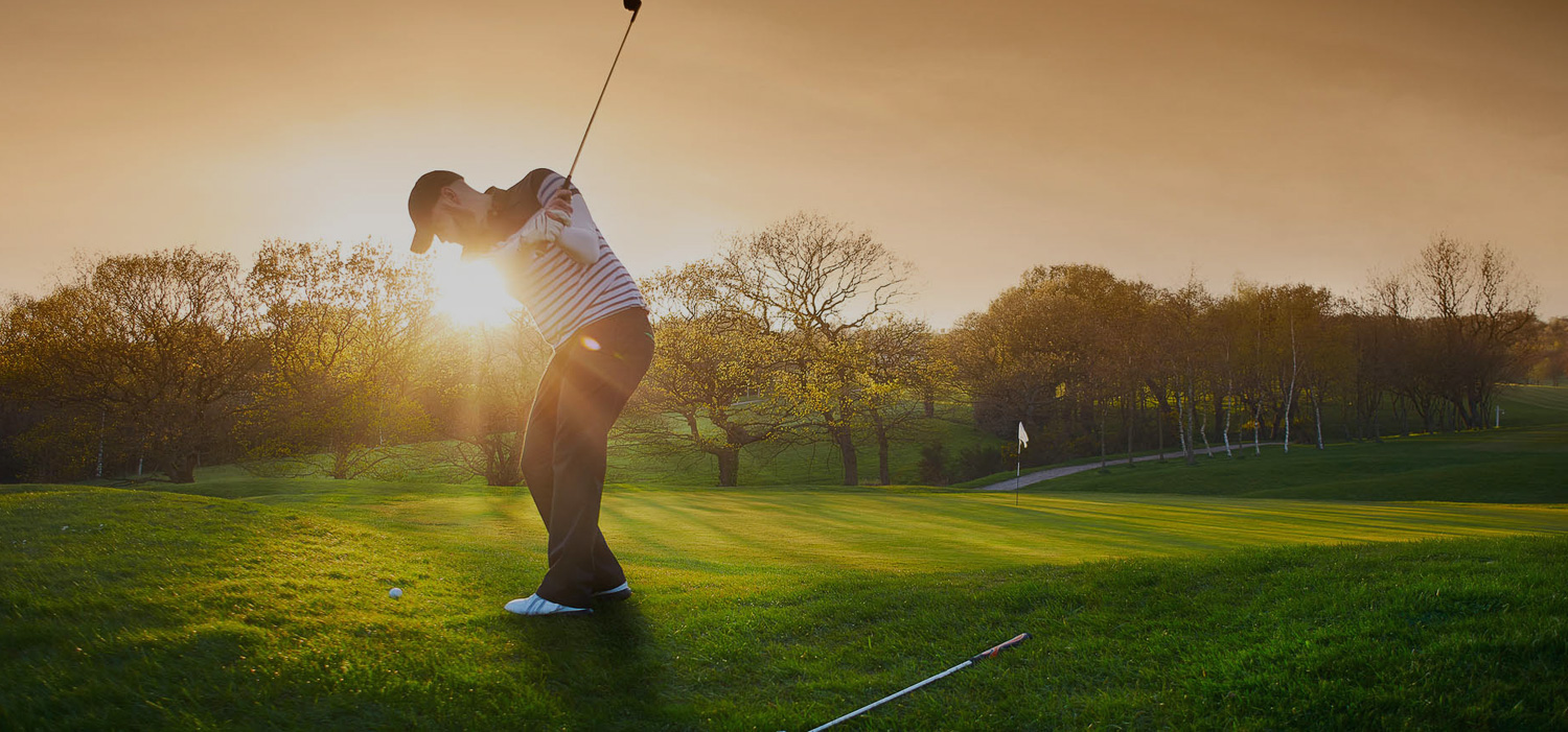 Man playing golf at the golf course and a sunlight behind him