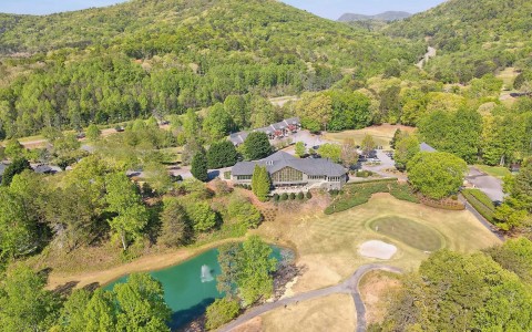 aerial view of a landscape with a lake and hole golf course around a property 