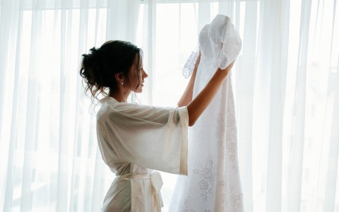 fiancee in robe looking at her wedding dress