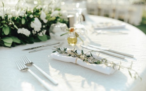 closeup view of a table decorated for a wedding with a boutique of white roses in the center of the table