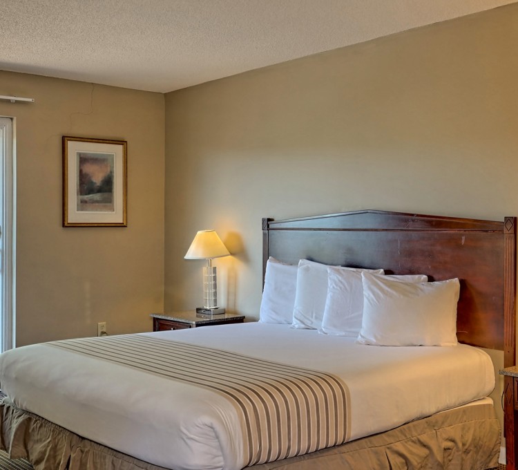 View of a bed of a hotel with two nightstands by the sides and a paint on the wall