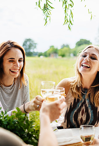 women toasting with glasses of white wine outside
